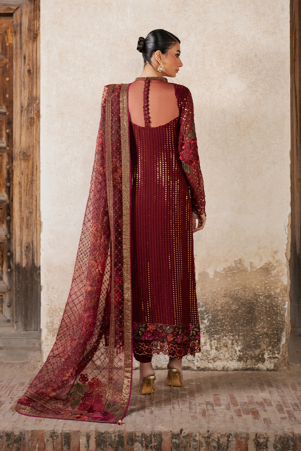Close-up of detailed embroidery on maroon chiffon dress with floral and butterfly designs, gold thread, and embellishments
