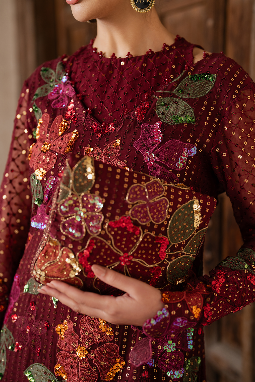 Close-up of embroidered maroon dress with floral sequin embroidery and matching clutch, traditional Pakistani outfit