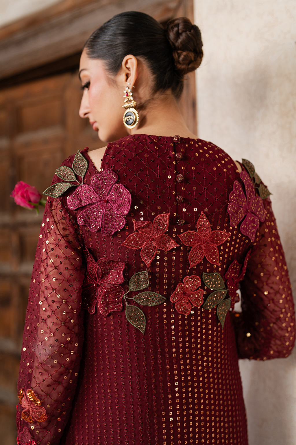Model wearing embroidered maroon chiffon dress with floral embroidery, traditional Pakistani fashion